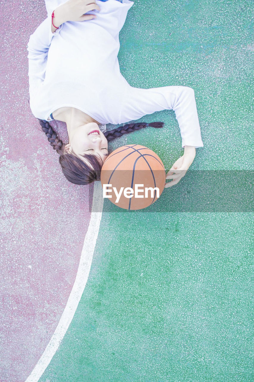 Directly above shot of young woman lying down at basketball court