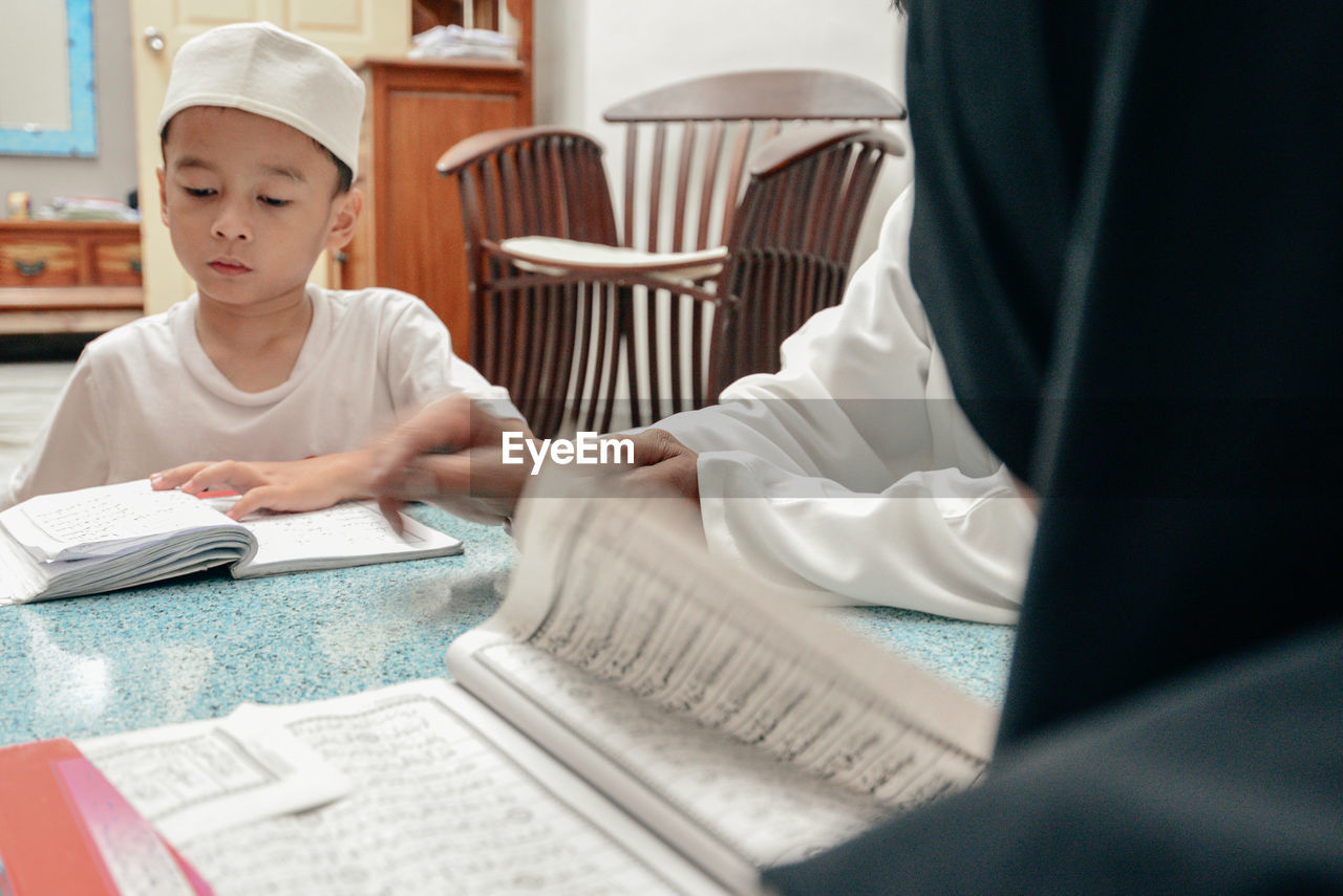 Boy reading koran while sitting at home