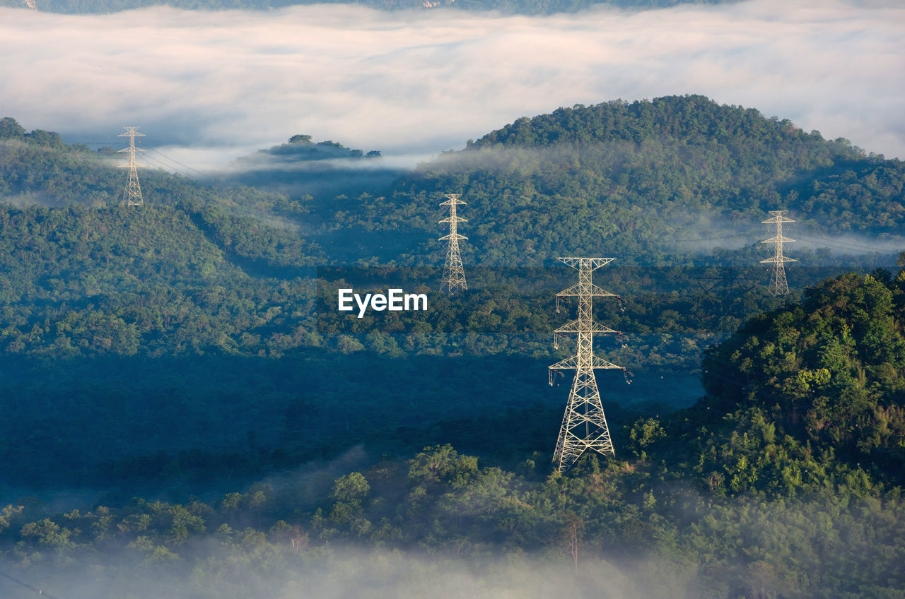 Transmission tower in green forest and morning smooth fog. energy and environment concept. 
