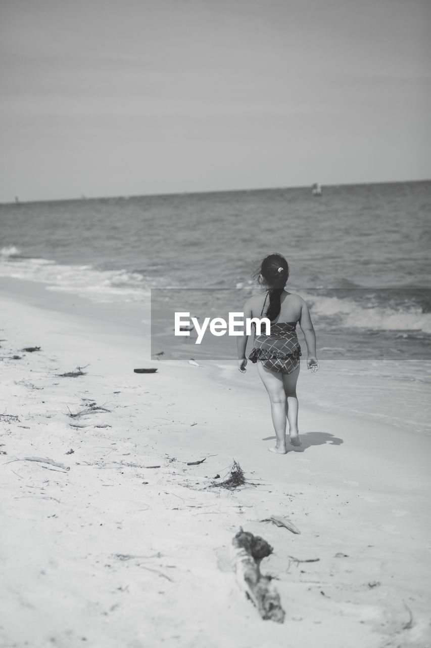 Full length of girl walking at beach against sky