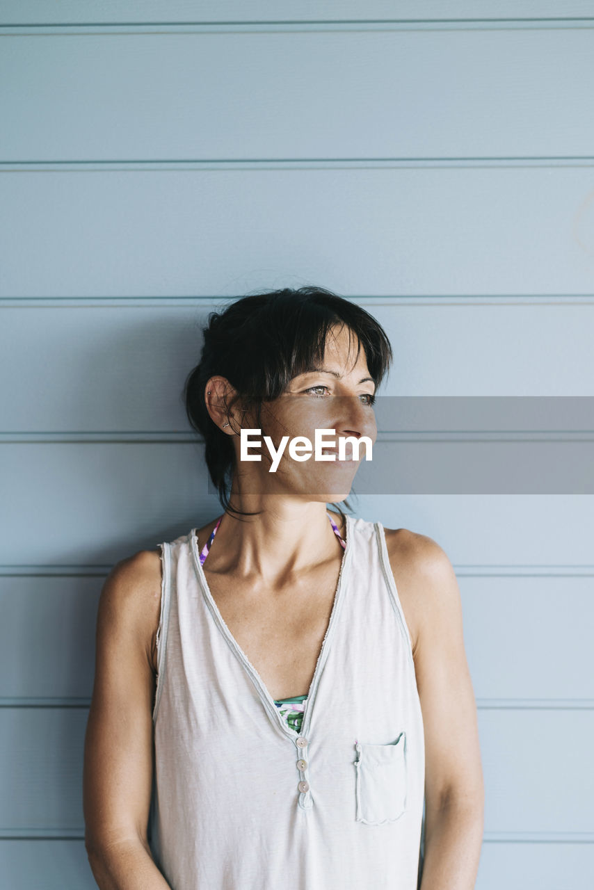 Smiling woman standing against wall