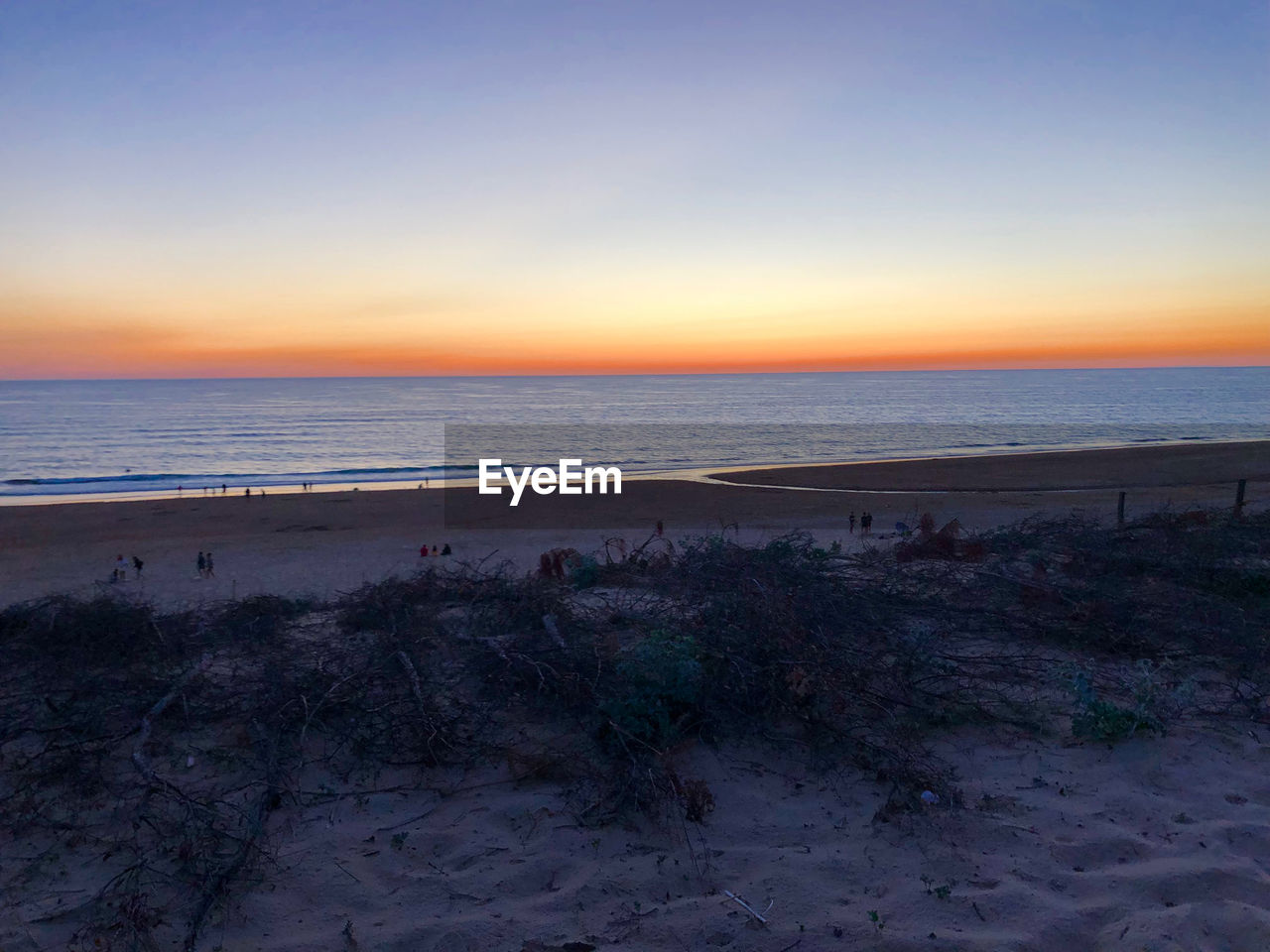 SCENIC VIEW OF BEACH AGAINST SKY AT SUNSET