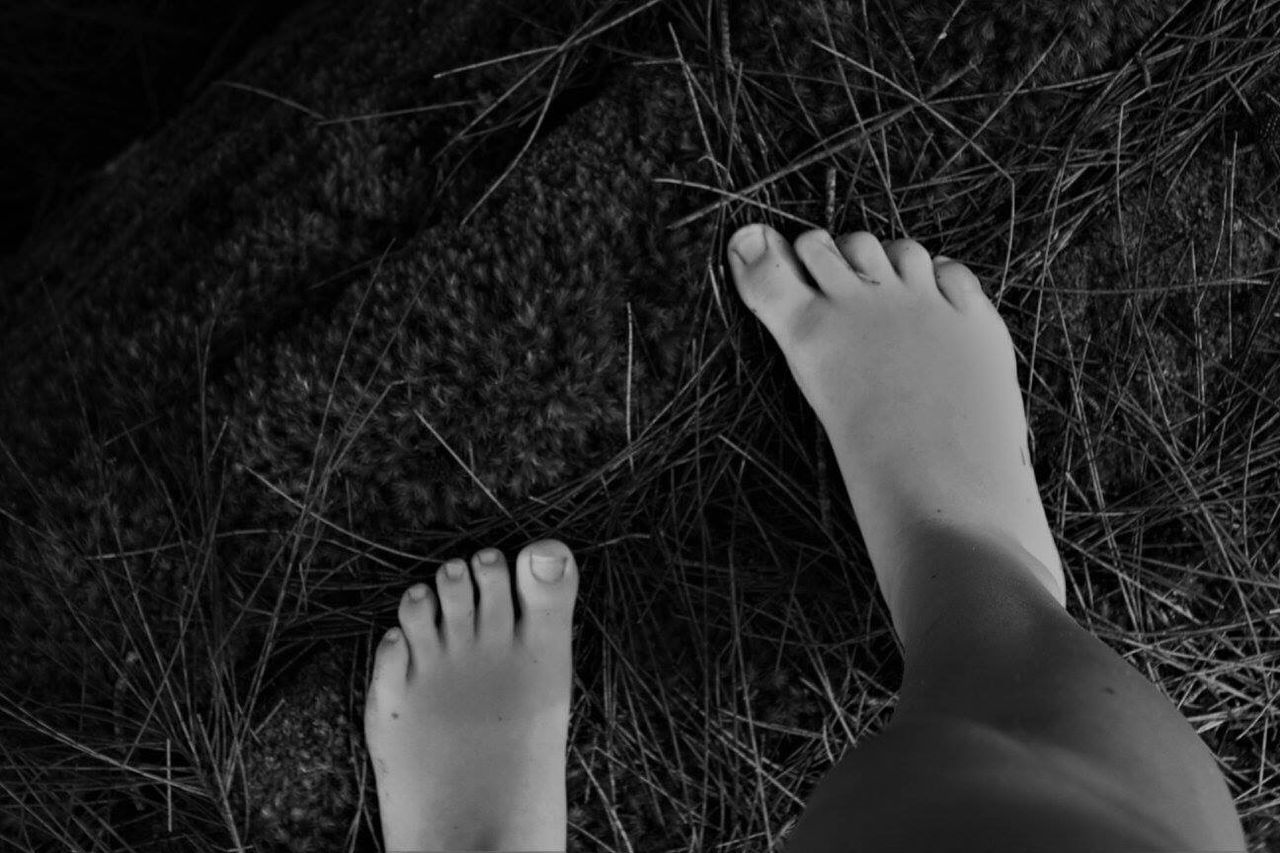 LOW SECTION OF WOMAN RELAXING AGAINST BARE FEET