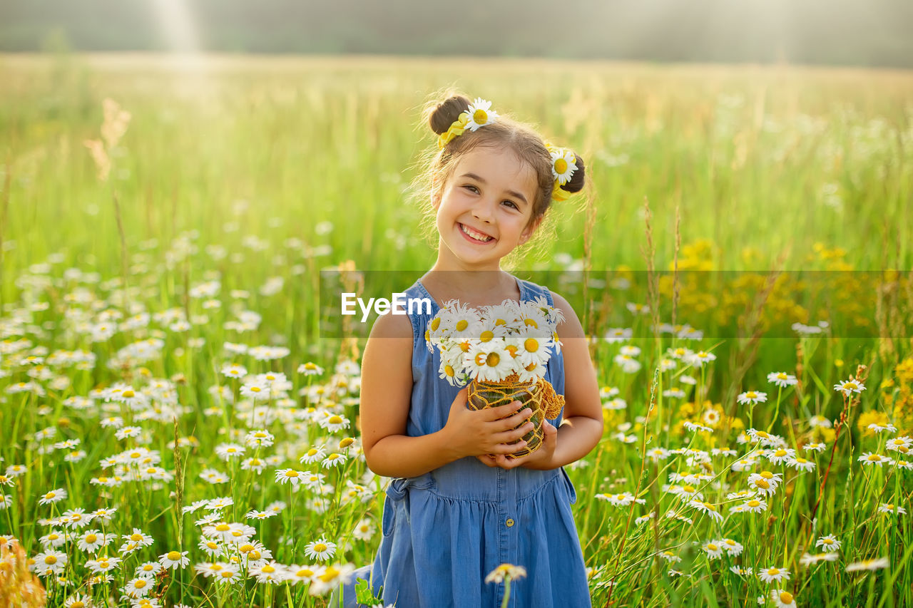 Cute smiling little girl with a bouquet of daisies