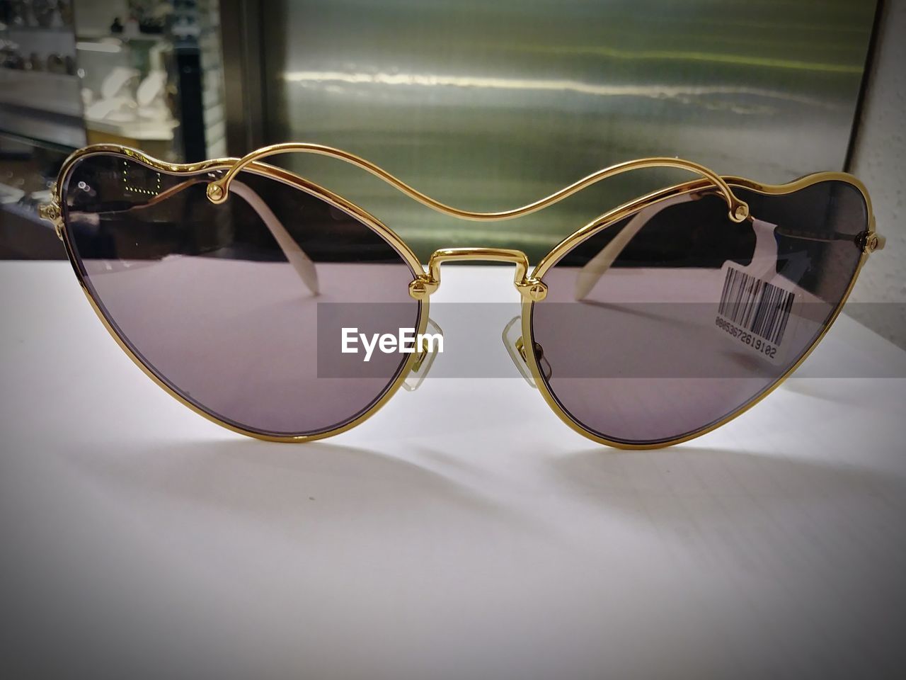 CLOSE-UP OF SUNGLASSES WITH REFLECTION ON TABLE