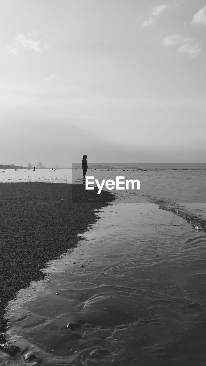 WOMAN ON BEACH AGAINST SKY