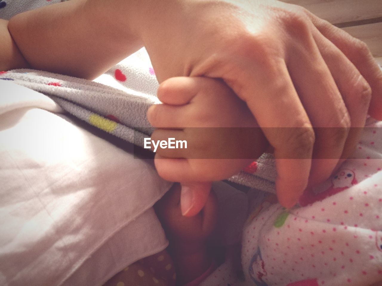 CLOSE-UP OF HANDS AND BABY ON BED