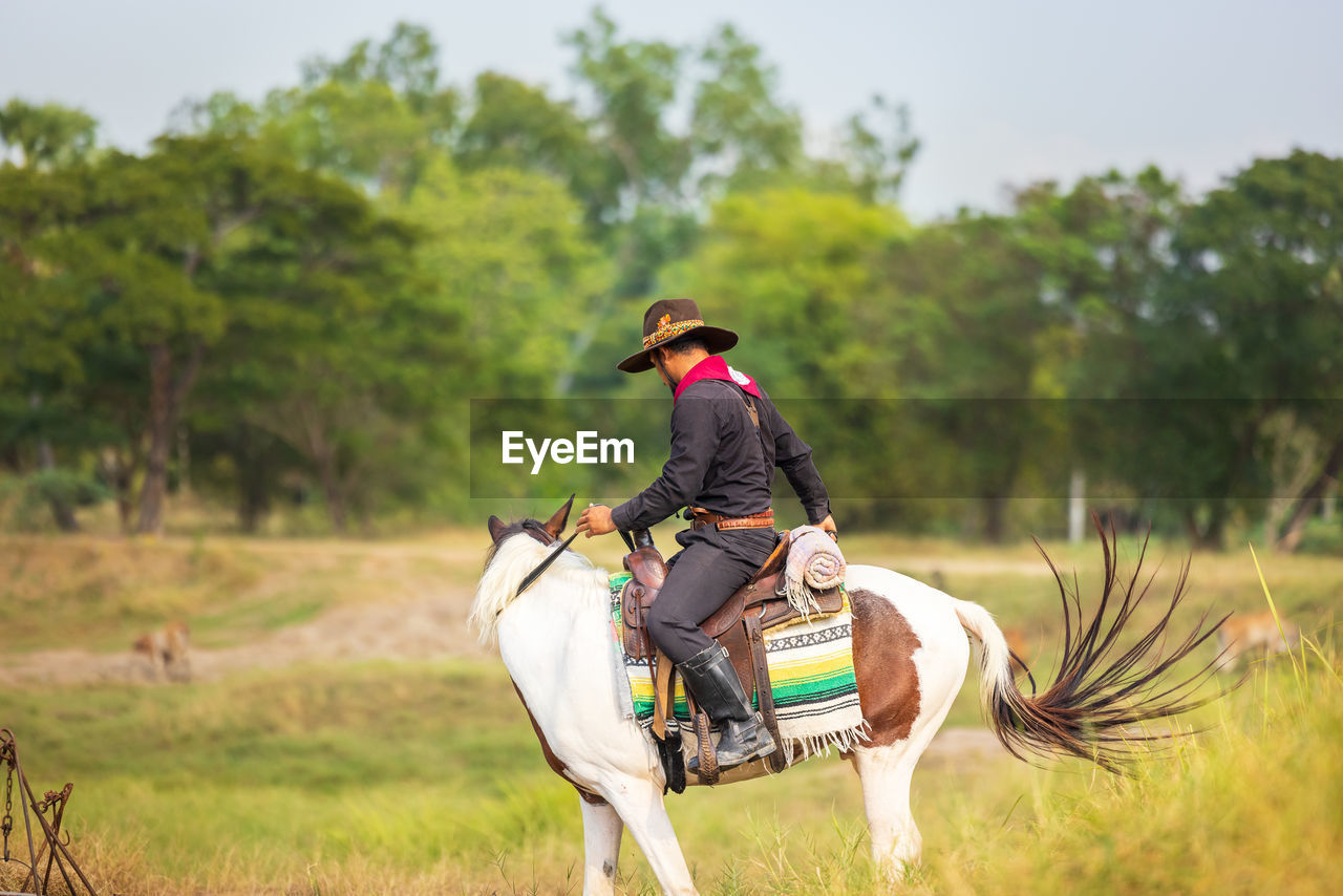 Cowboy's way of life include riding a horse around locales.