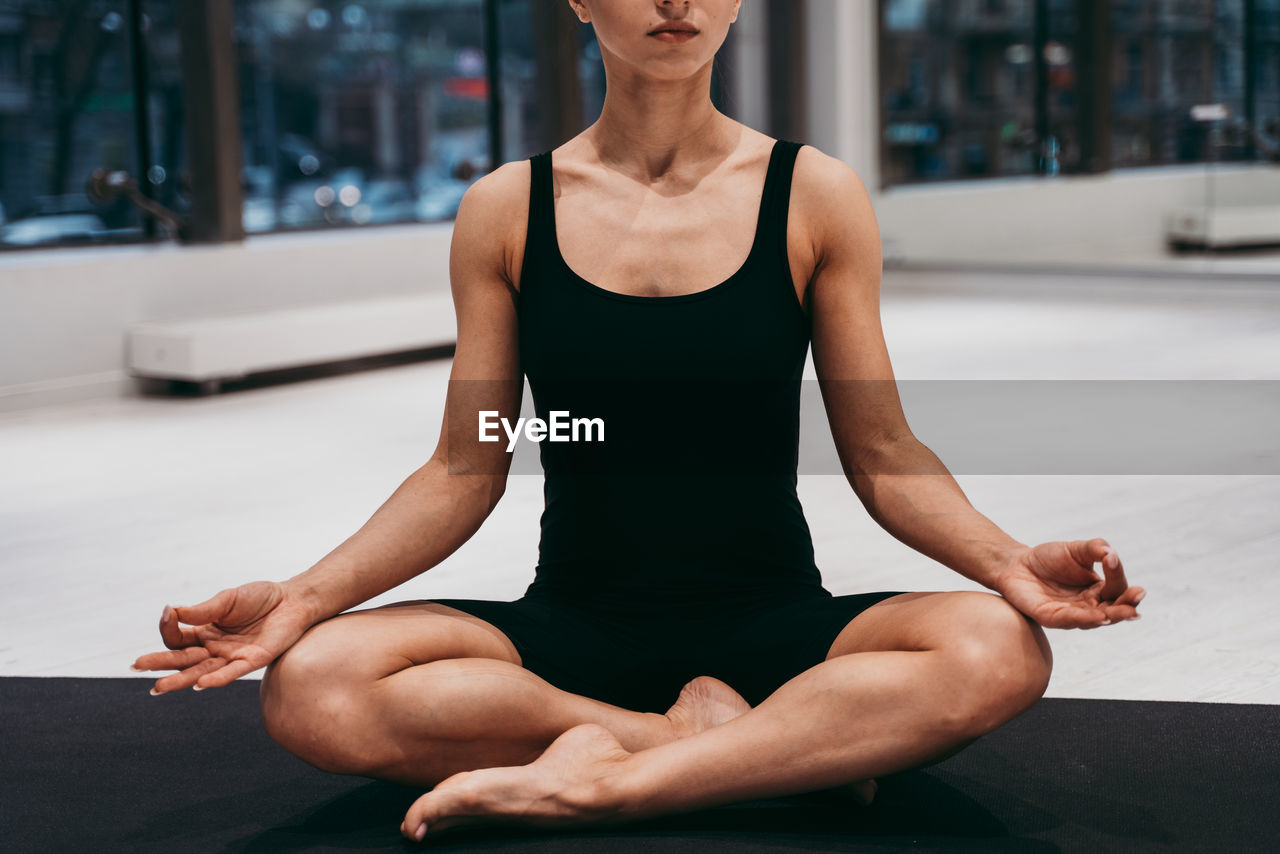 Low section of woman meditating at gym