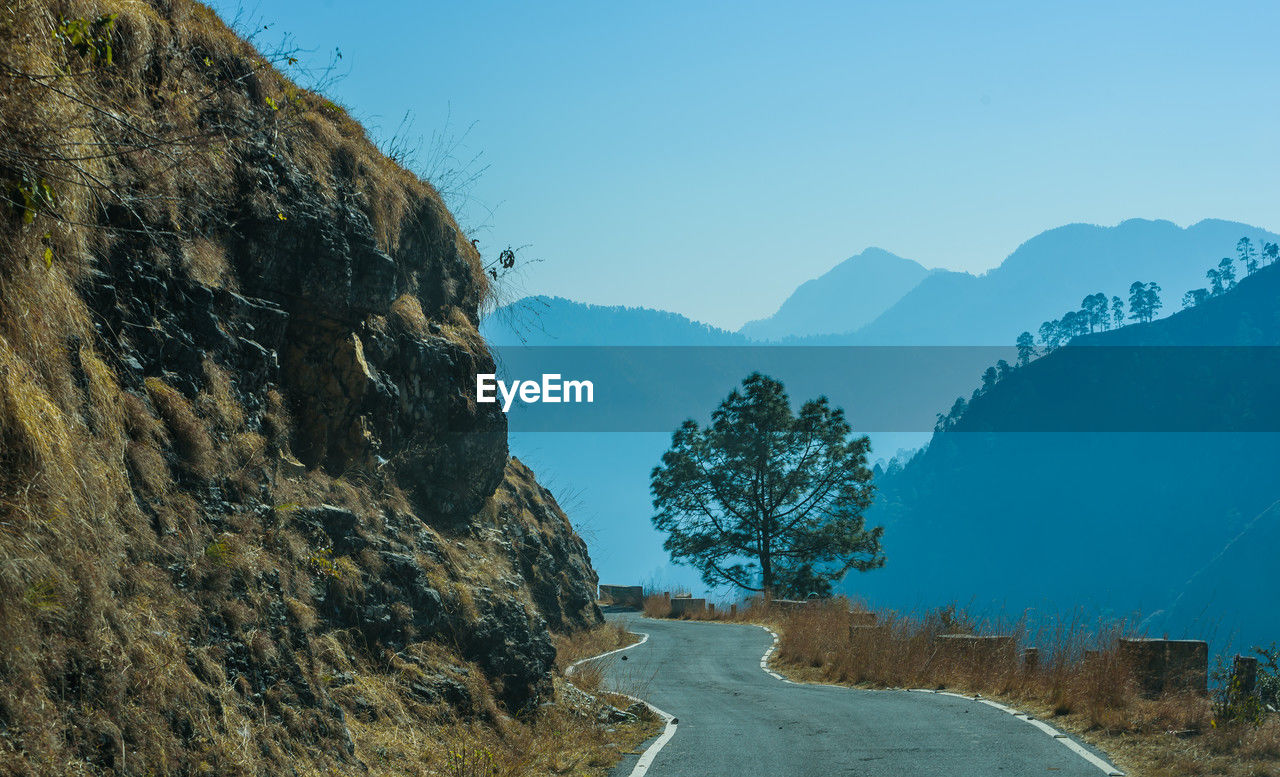 mountain, mountain range, environment, sky, road, landscape, scenics - nature, nature, beauty in nature, transportation, valley, plant, tree, land, blue, ridge, no people, travel, mountain pass, wilderness, tranquility, clear sky, terrain, travel destinations, outdoors, non-urban scene, the way forward, tranquil scene, plateau, rock, day, forest, water, pinaceae, tourism