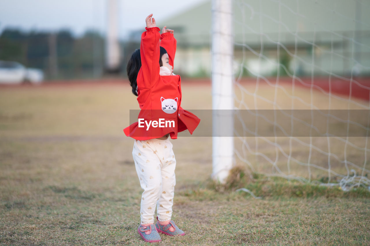 Full length of girl standing by soccer goal at field