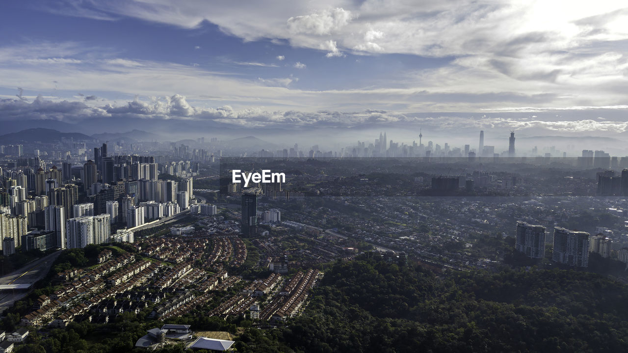 High angle view of city buildings against cloudy sky