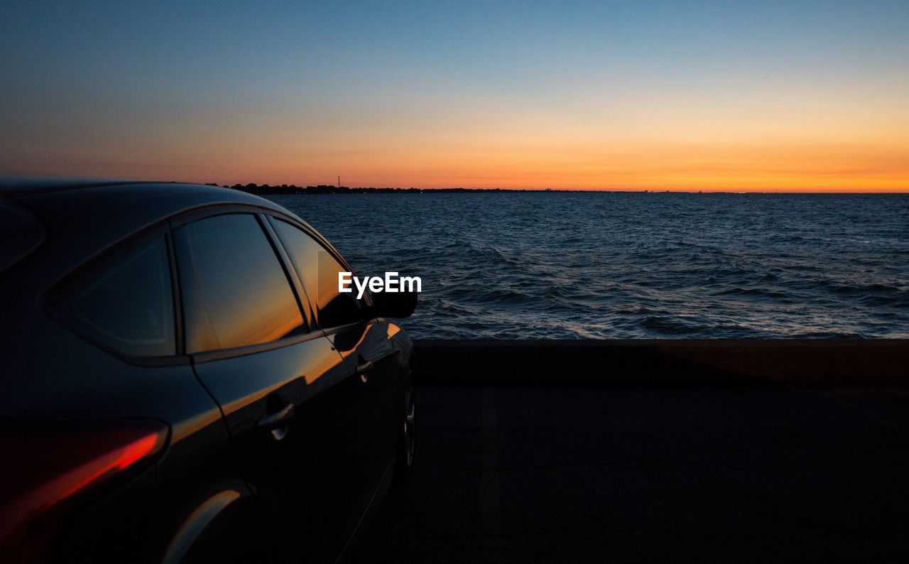 Close-up of car on sea against clear sky during sunset