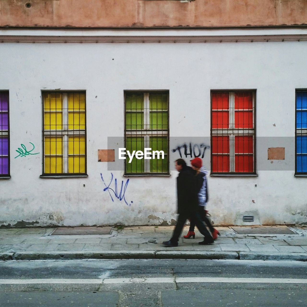 Man and woman walking on sidewalk by building