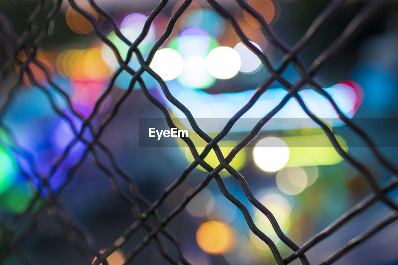 Defocused image of illuminated lights seen through fence