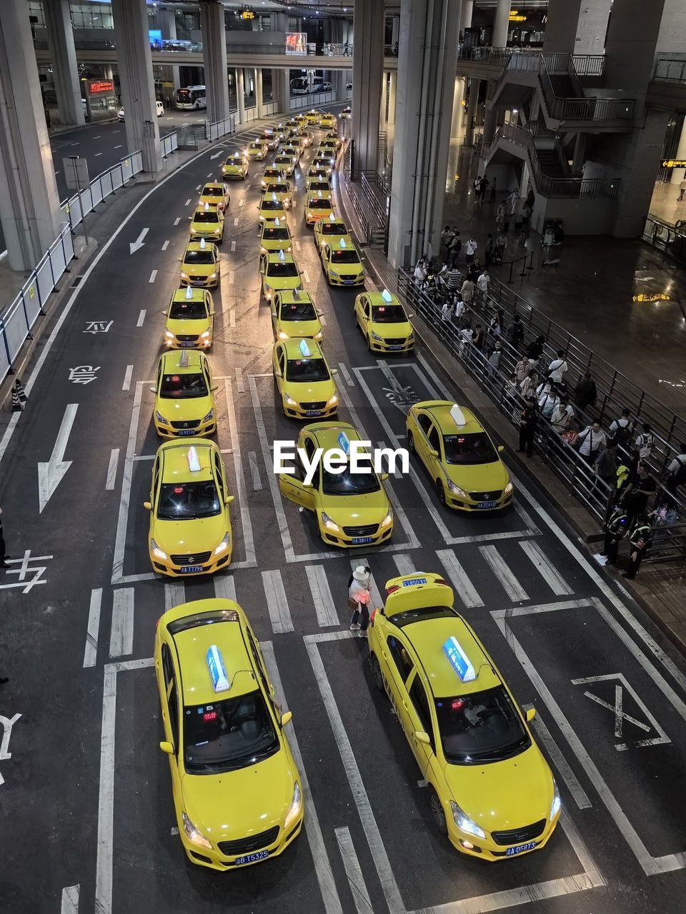 transportation, mode of transportation, car, motor vehicle, city, road, traffic, architecture, high angle view, street, city life, taxi, city street, sign, lane, road marking, land vehicle, yellow taxi, yellow, public transportation, marking, symbol, metropolitan area, motion, built structure, commuter, on the move, building exterior, travel, transport, traffic jam, vehicle, public transport, outdoors, traffic congestion, infrastructure, cityscape, day, highway, crossroad, travel destinations, road intersection