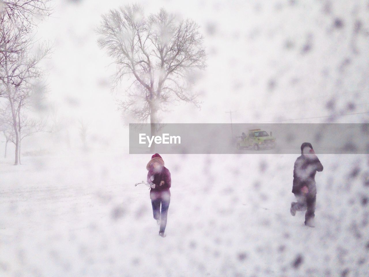 People on snow covered field seen through car window