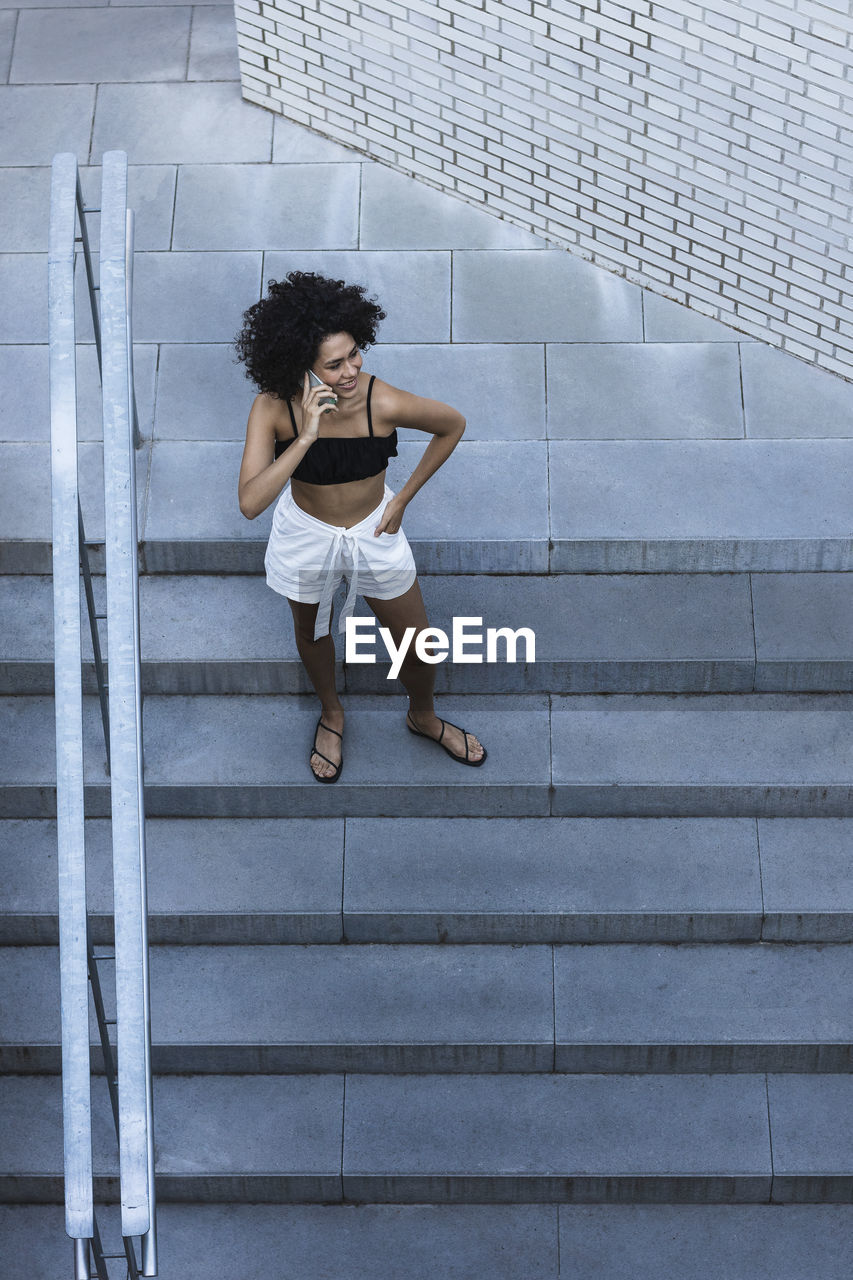 Young woman using smart phone while standing on steps