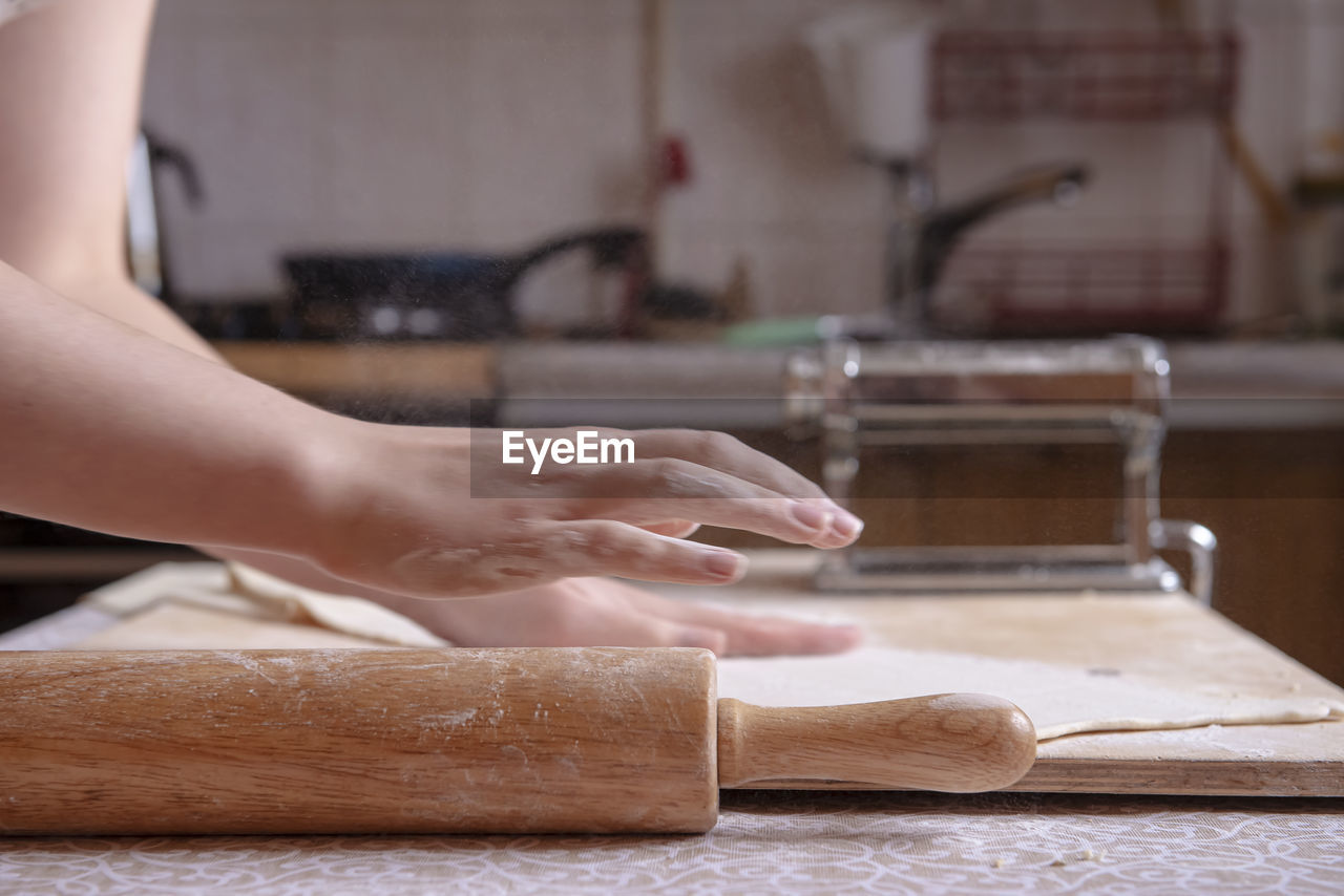 cropped hands of man cutting board on table