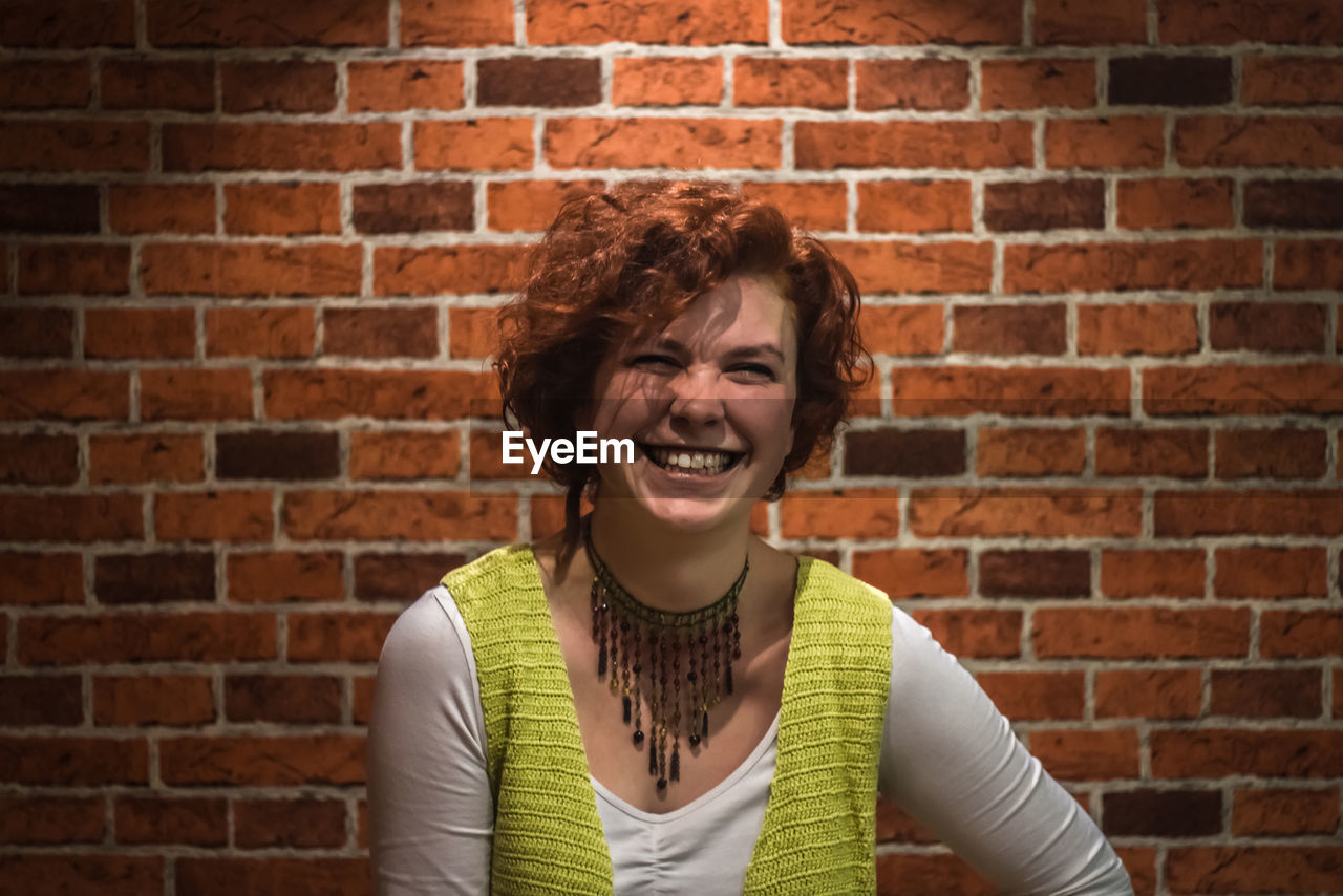 Portrait of woman against brick wall