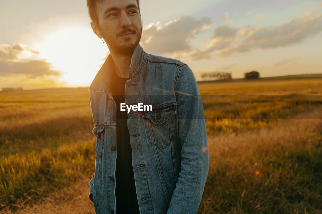 Man standing on field against sky during sunset