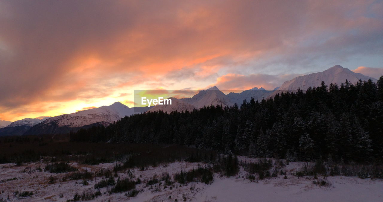 SCENIC VIEW OF SNOWCAPPED MOUNTAINS AGAINST ORANGE SKY