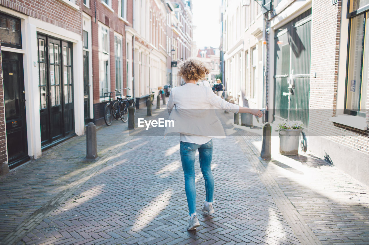 Rear view of mid adult woman walking on street in city