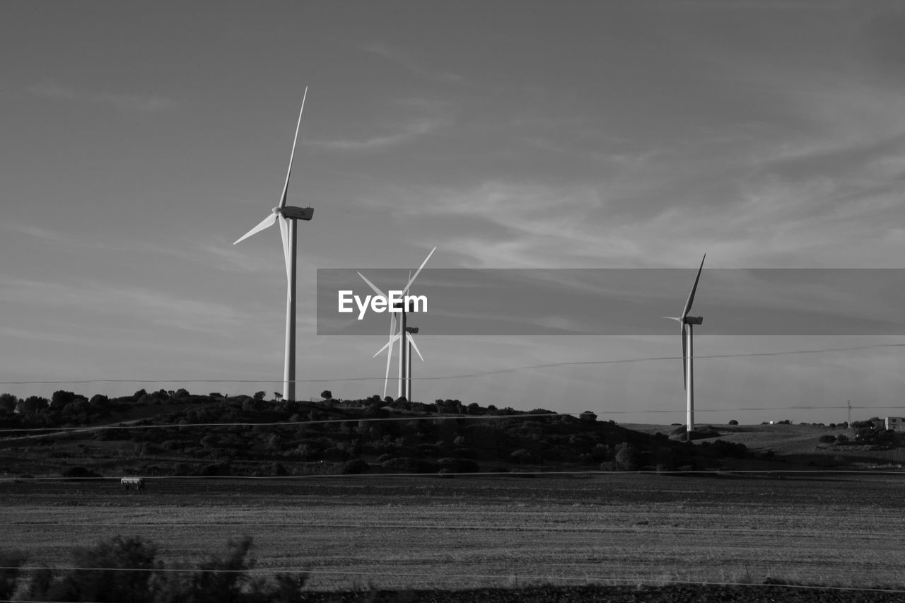 Windmills on field against sky