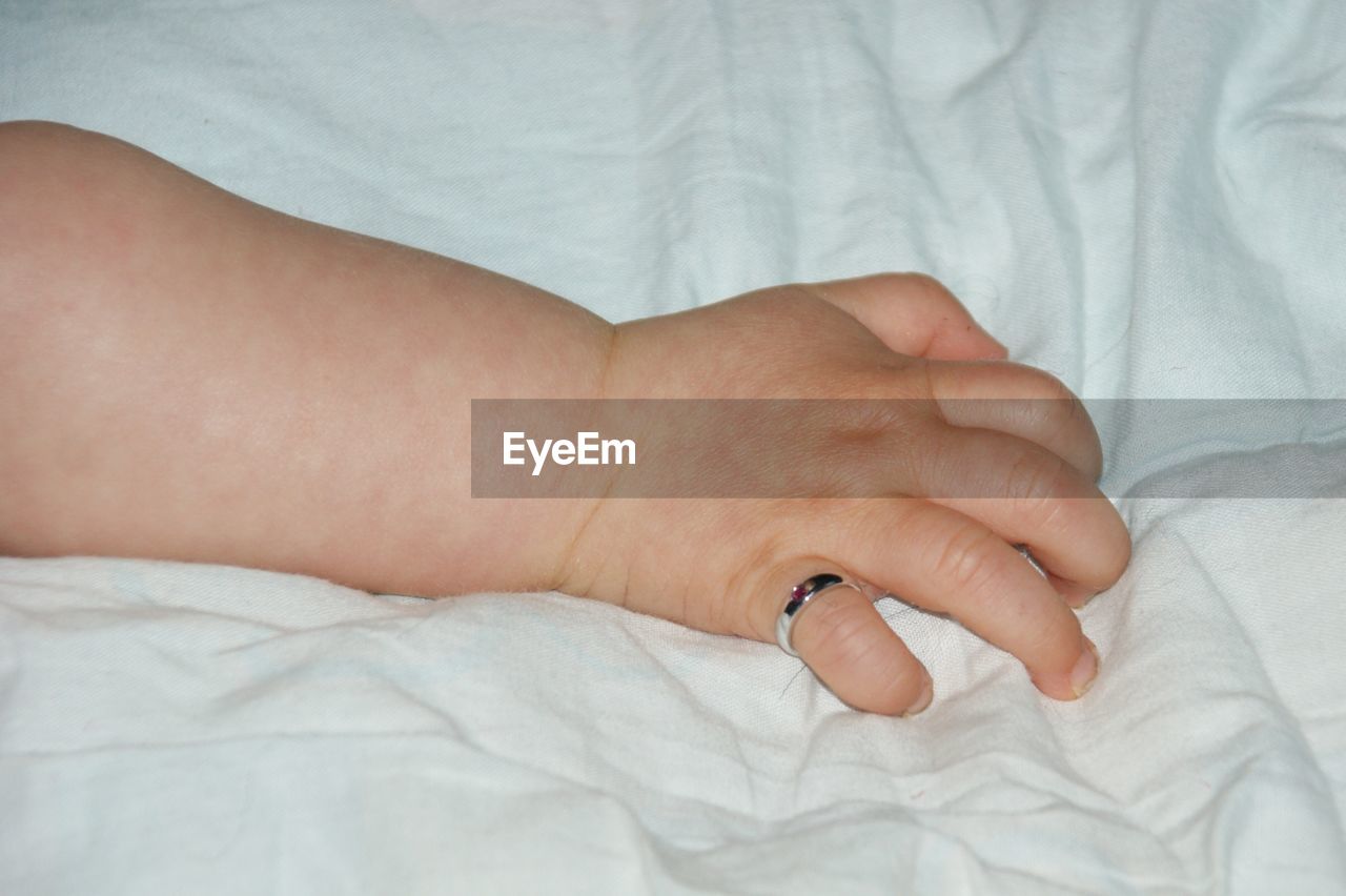 CLOSE-UP OF HAND ON WHITE BED