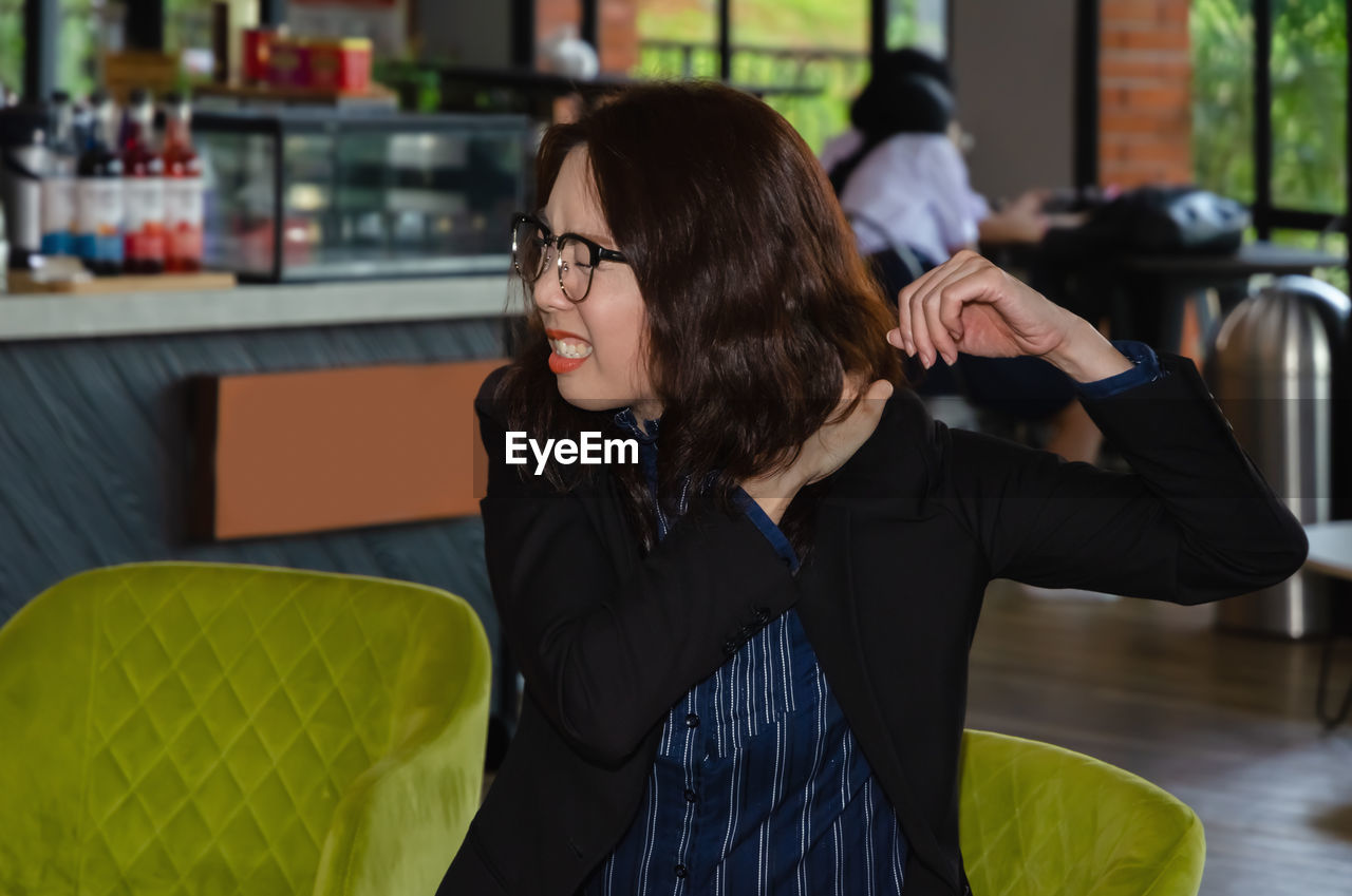 Close-up of woman with shoulder pain sitting at cafe