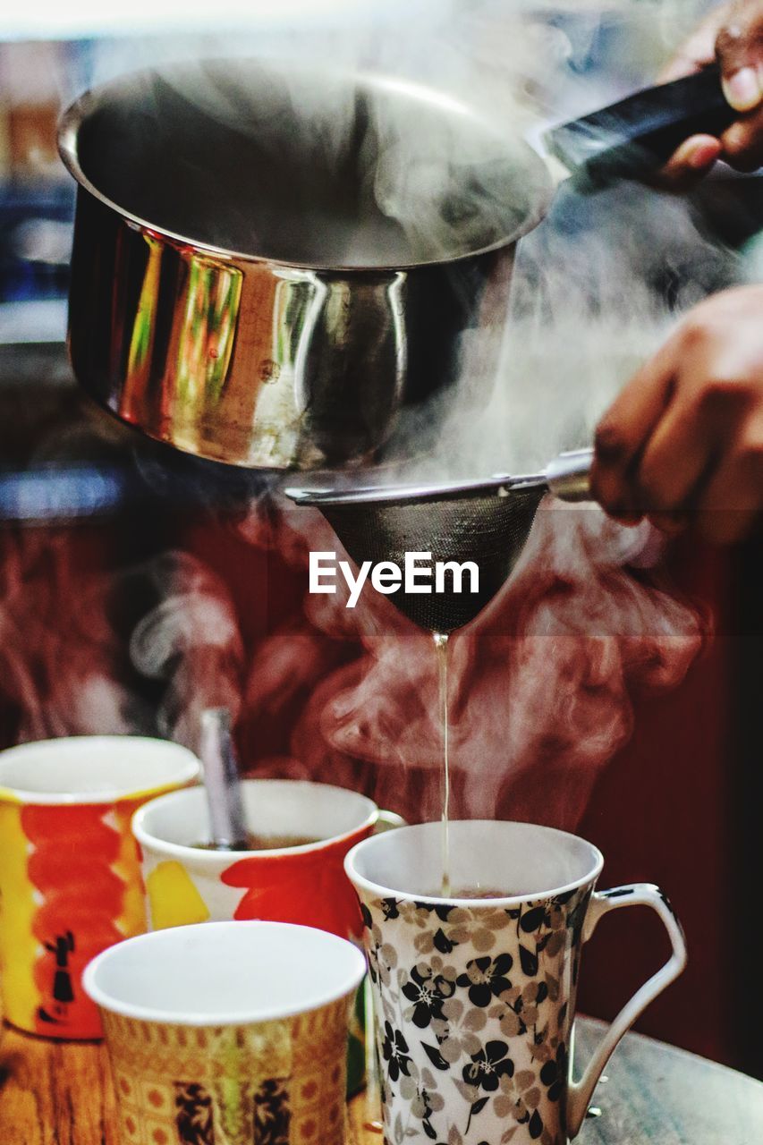 CLOSE-UP OF PERSON POURING TEA IN CUP