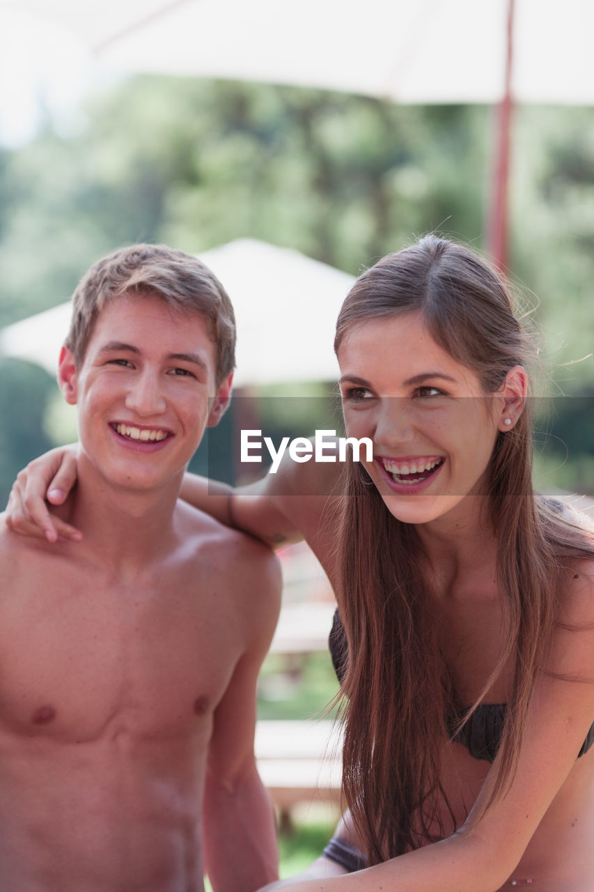 Portrait of cheerful shirtless man with girlfriend at park