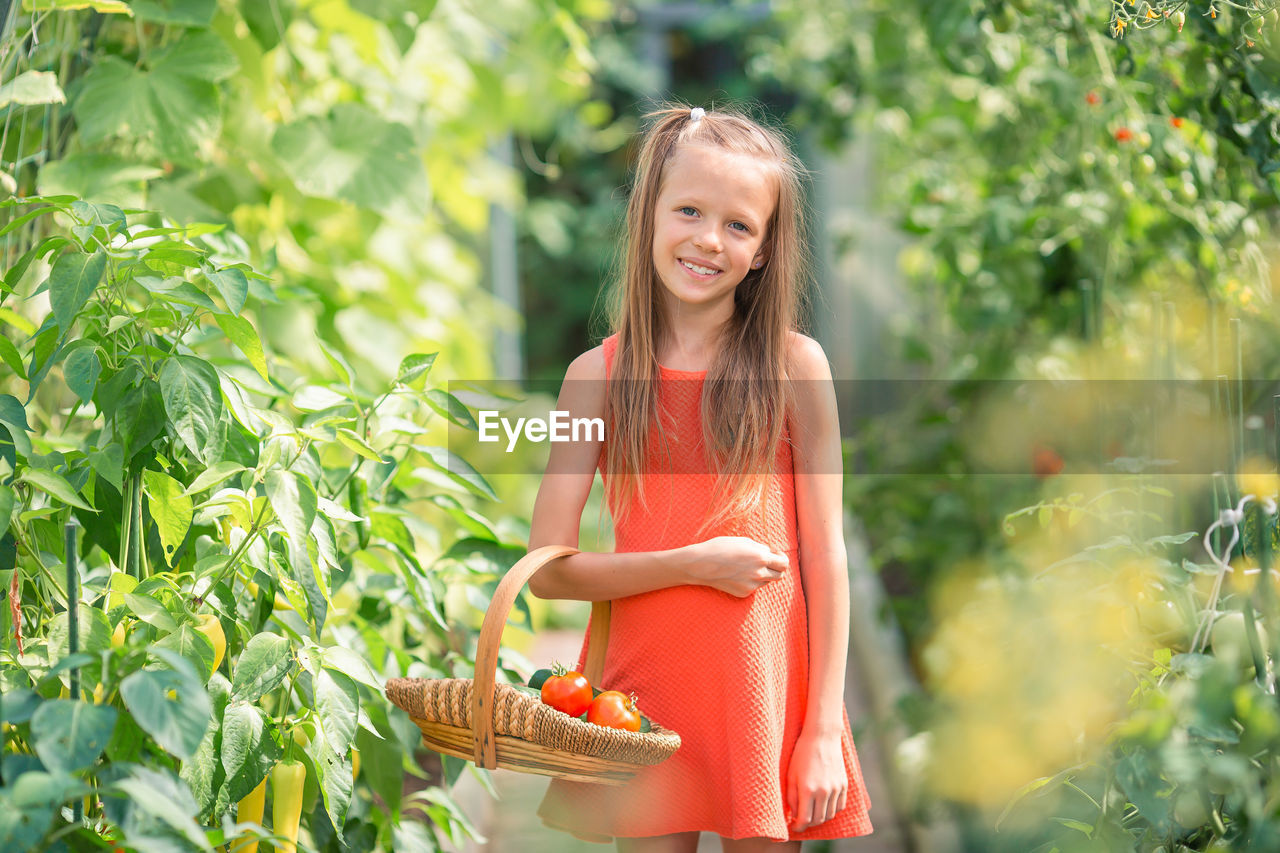 portrait of smiling young woman standing against plants