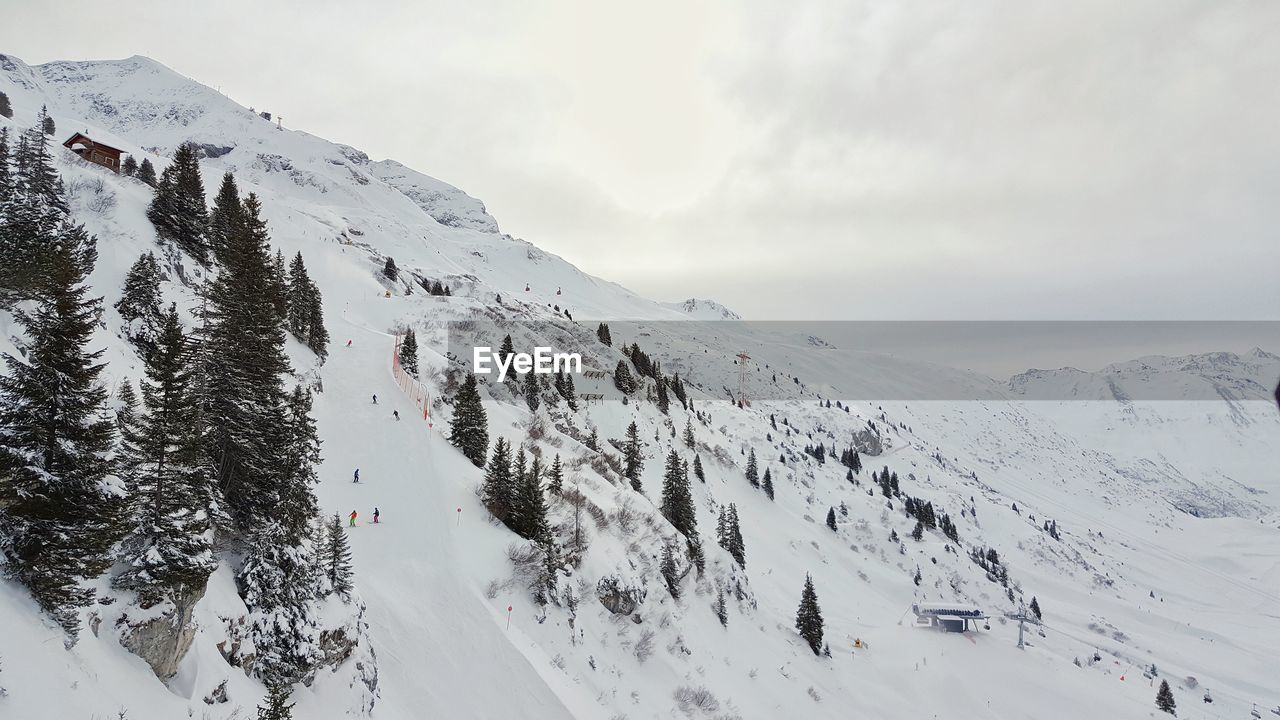 Scenic view of snow covered mountains against cloudy sky