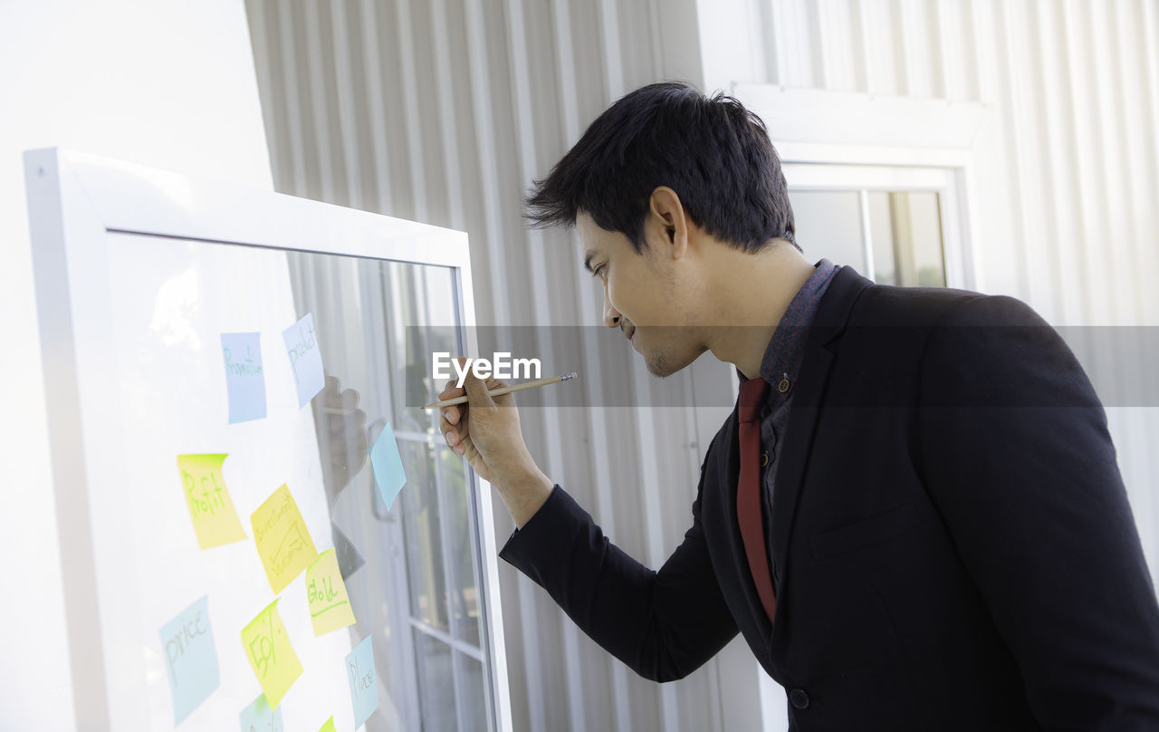 Businessman writing on glass at office