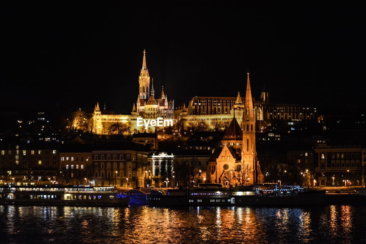 VIEW OF ILLUMINATED BUILDINGS AT WATERFRONT