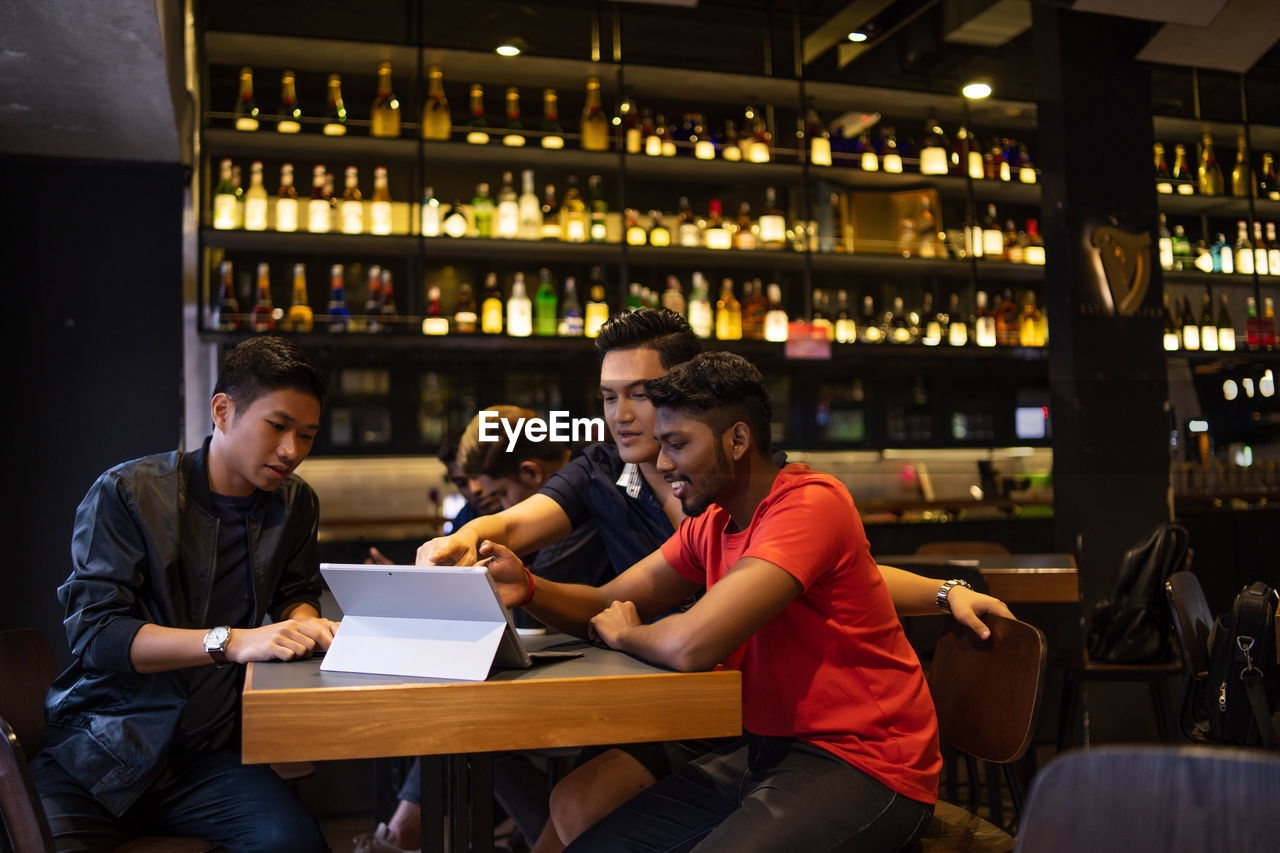 Friends using laptop while sitting in restaurant
