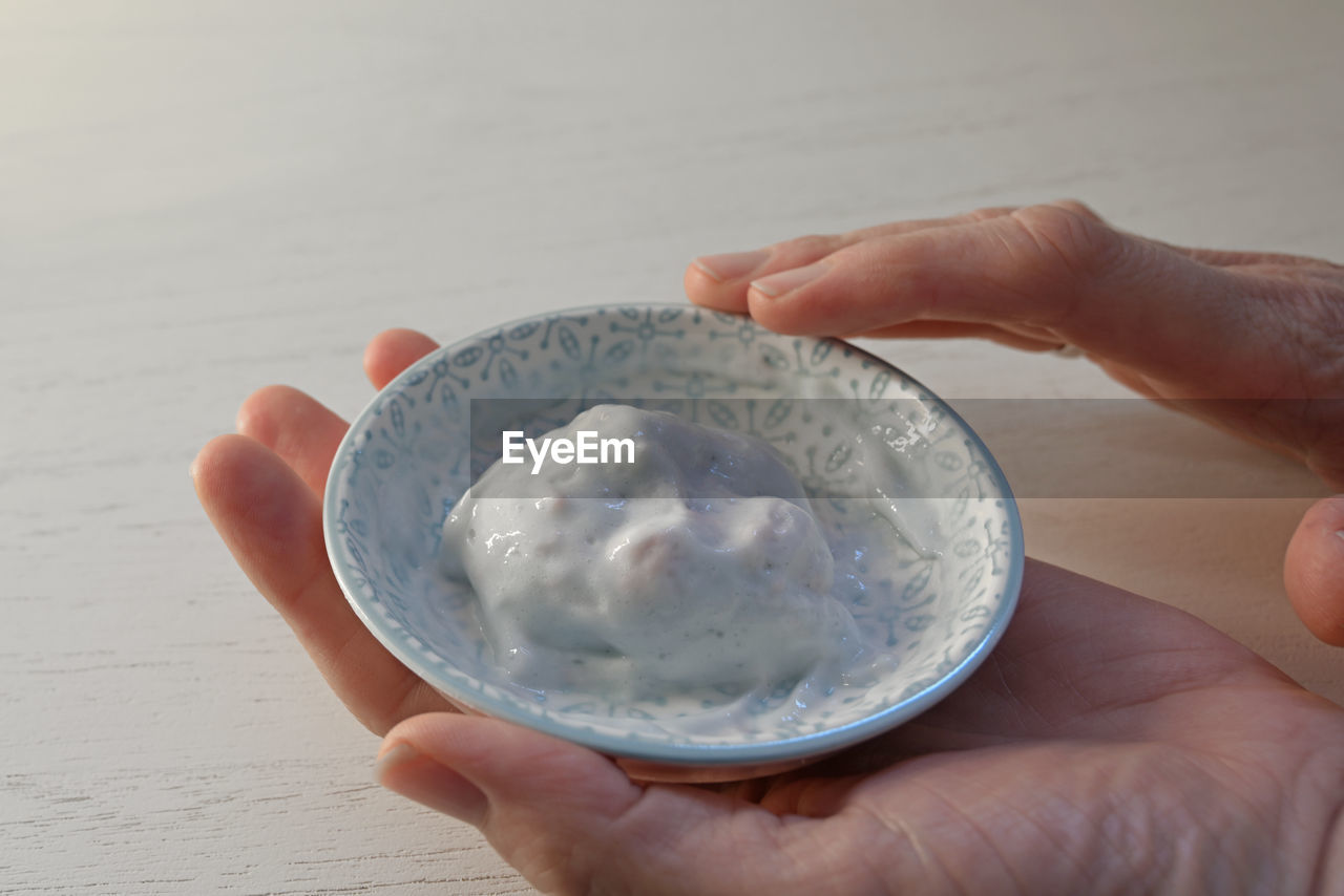 CLOSE-UP OF HAND HOLDING ICE CREAM