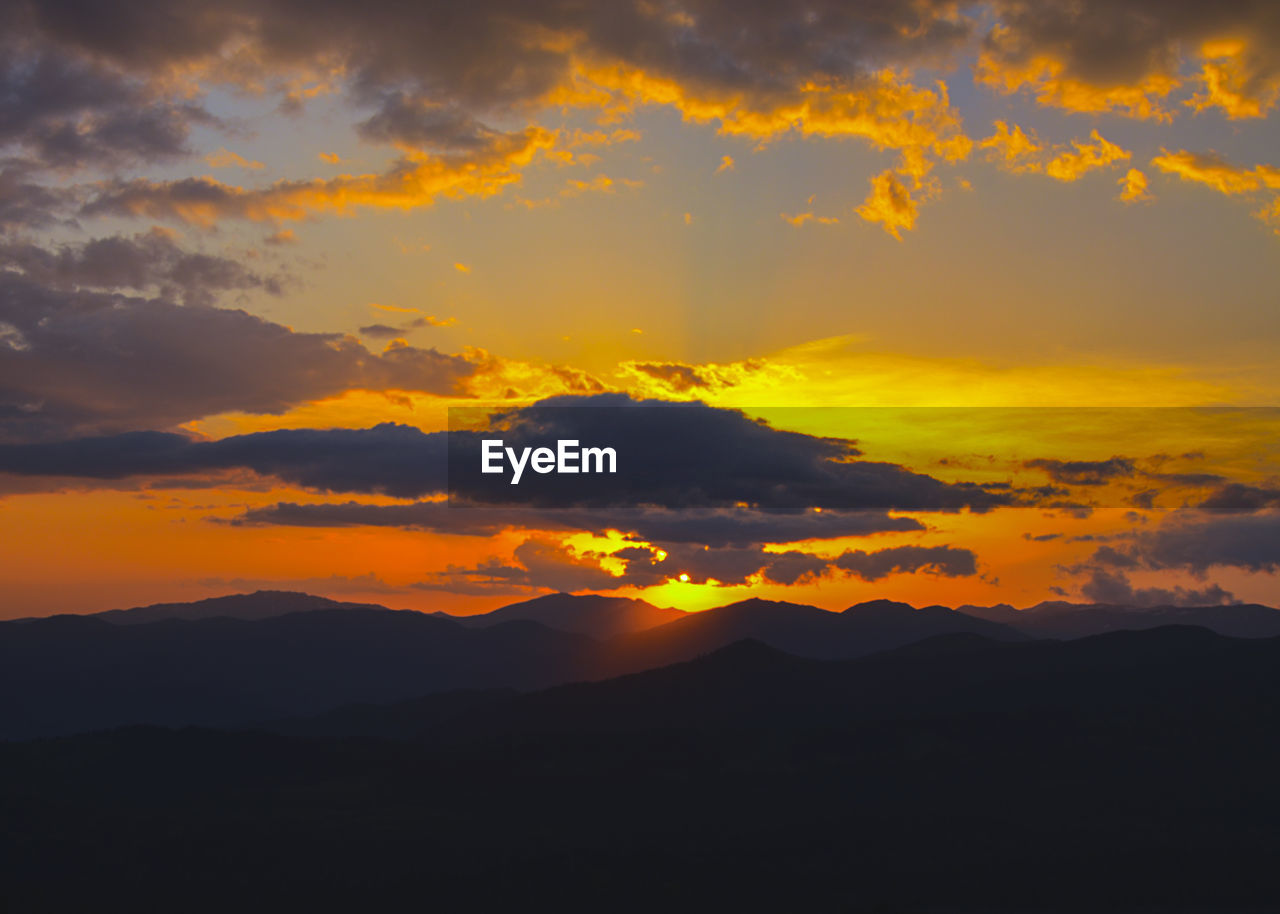 Scenic view of silhouette mountains against orange sky