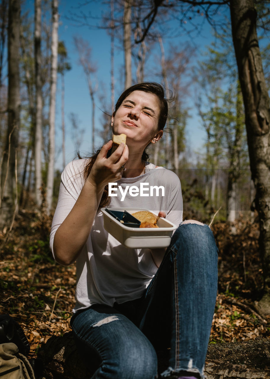 Happy woman eating food in forest