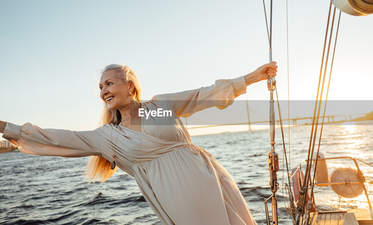 Smiling senior woman on sailboat in sea against sky