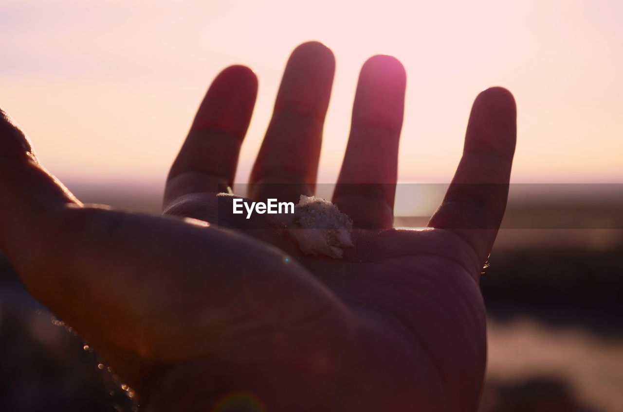 CLOSE-UP OF HUMAN HAND AGAINST SKY