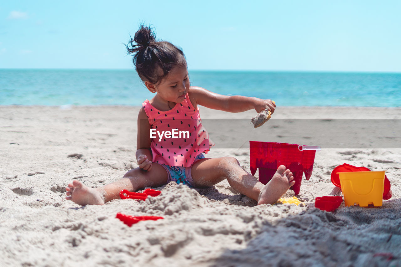 Rear view of woman sitting on sand at beach