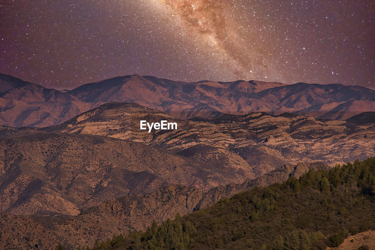 SCENIC VIEW OF MOUNTAIN RANGE AGAINST STAR FIELD