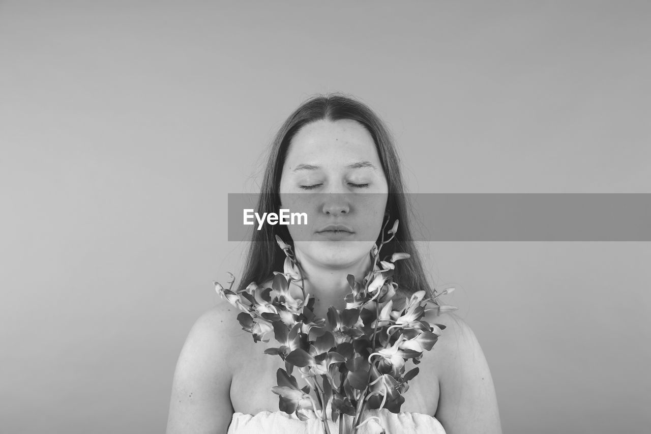 Beautiful young woman with eyes closed against gray background