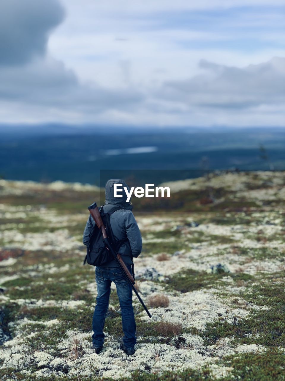 Rear view of man with backpack standing on land against sky