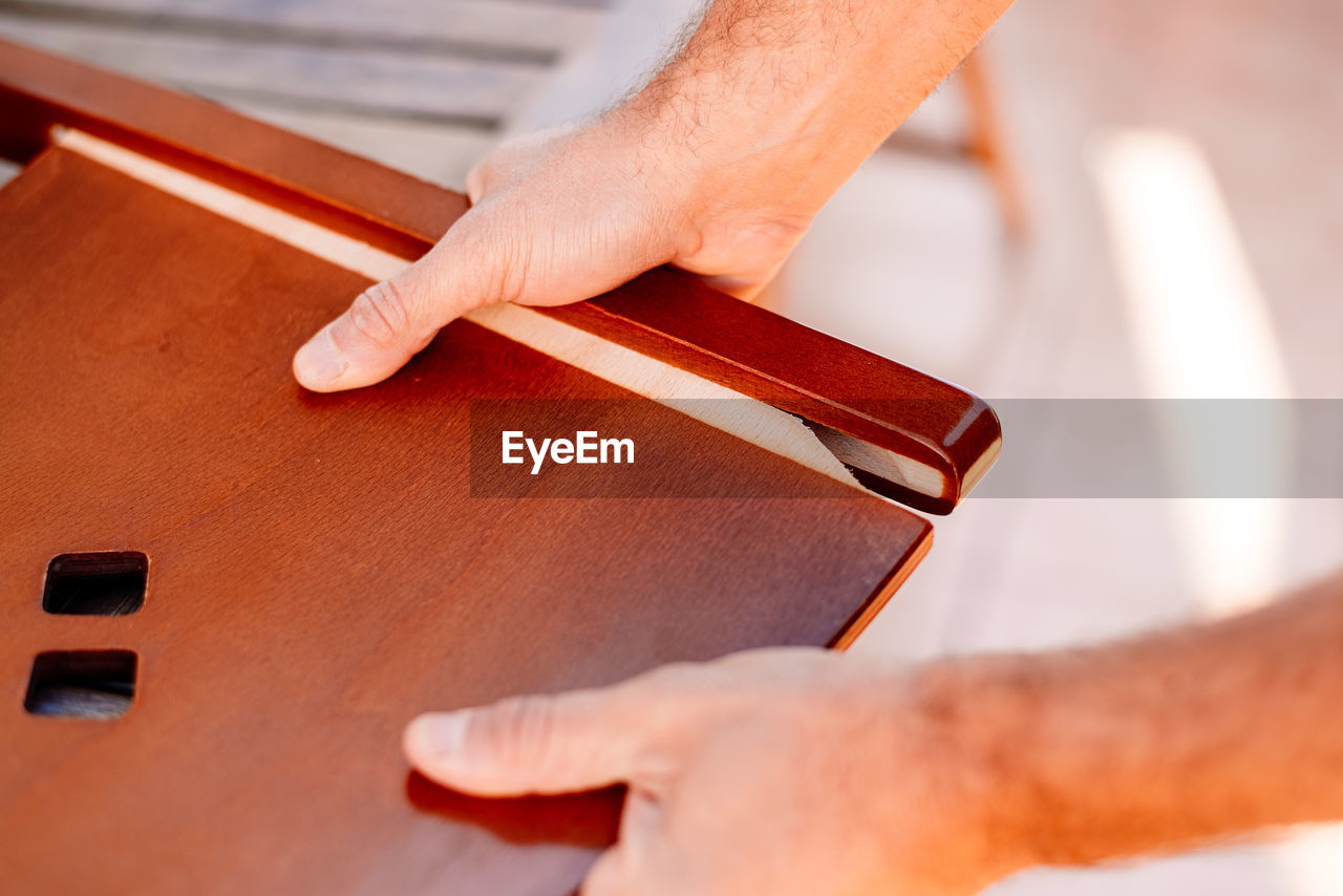 hand, adult, one person, occupation, wood, holding, indoors, skill, string instrument, close-up, working, men, red, selective focus, craft, business