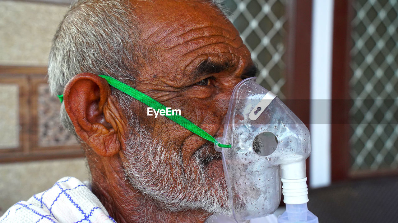 A elder person infected with covid 19 disease. patient inhaling oxygen wearing mask with liquid oxy