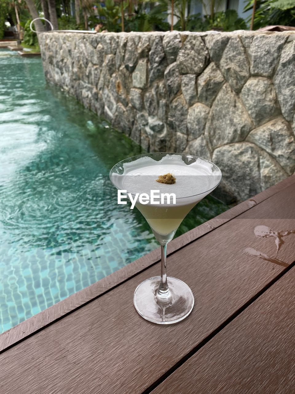 Glass of water on table by swimming pool