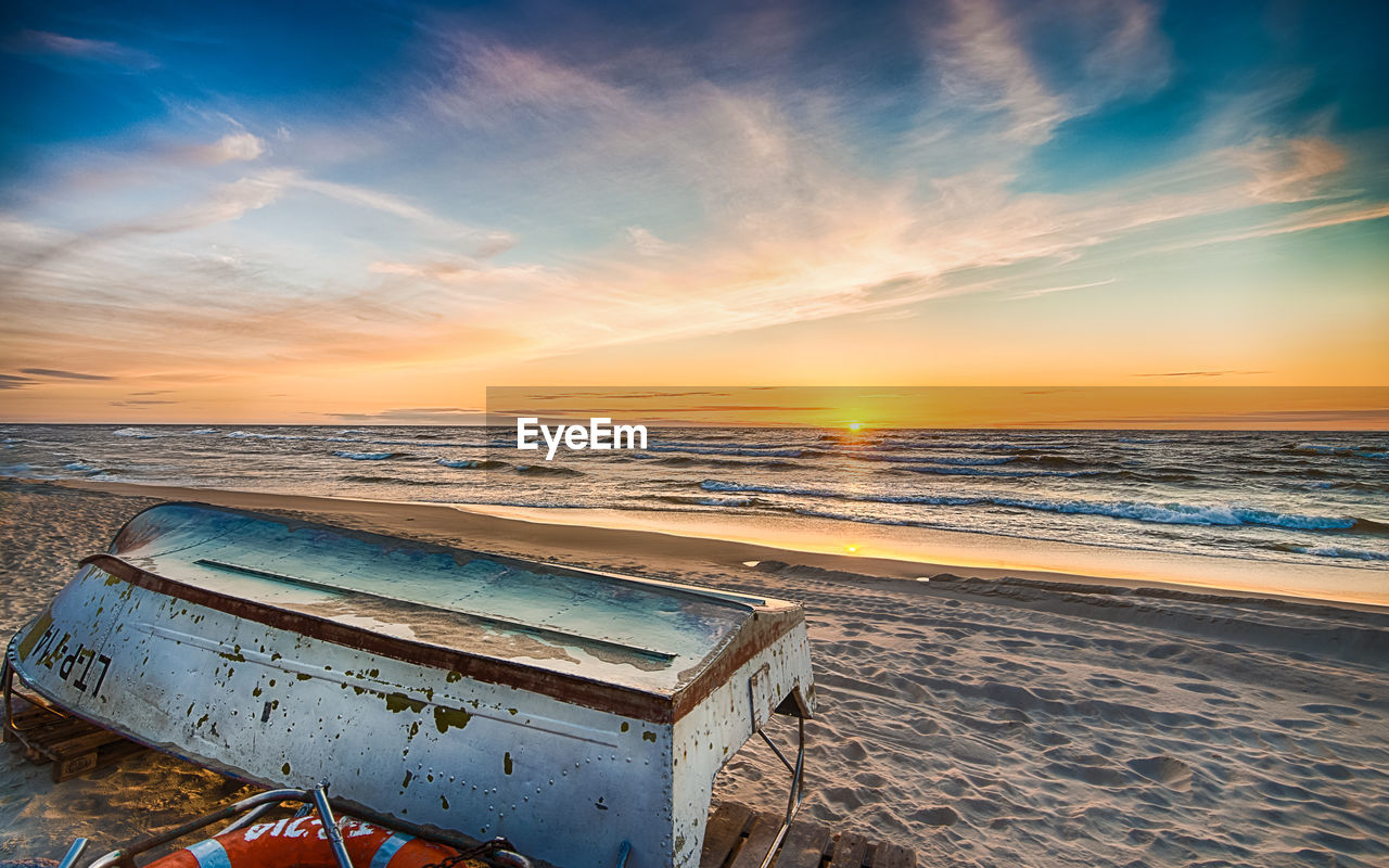 Close-up of beach against dramatic sky during sunset